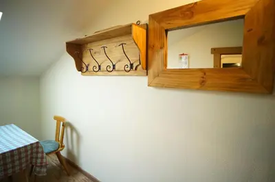 a mirror on a wall with a table and a chair at Gstattlhof Mountain Farmhouse in Braies