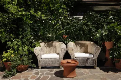 two wicker chairs and a toilet in a courtyard at Hotel Sparerhof in Vilpiano