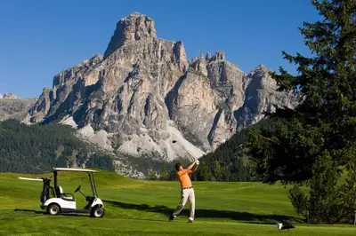 a man hitting a golf ball with a golf cart at Villa Ortensia in San Vigilio Di Marebbe