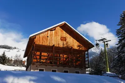 a wooden barn in the snow with a ski lift at Villa Ortensia in San Vigilio Di Marebbe