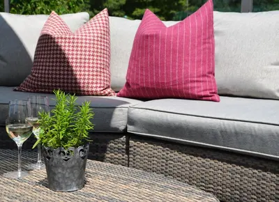 a couch with pink pillows and a glass of wine at Royal Hotel Hinterhuber in Brunico