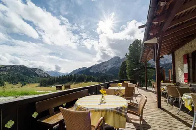 a table on a deck with a view of mountains at Hohe Gaisl in Braies