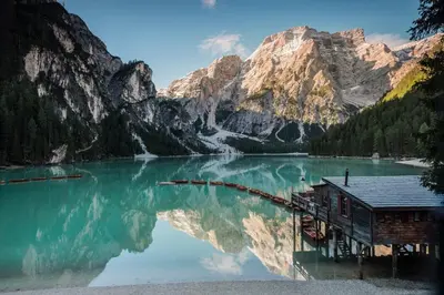 a house on a lake in front of a mountain at Hohe Gaisl in Braies