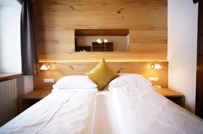 a bed with white sheets and a yellow pillow at Hohe Gaisl in Braies
