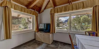 a living room with two windows and a television at Appartamento Luna in Campitello di Fassa