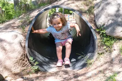 a little girl is sliding down a play tunnel at Hotel Langeshof in Anterivo