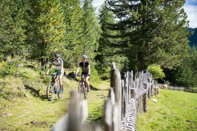 two people riding bikes down a path next to a zebra at Hotel Langeshof in Anterivo