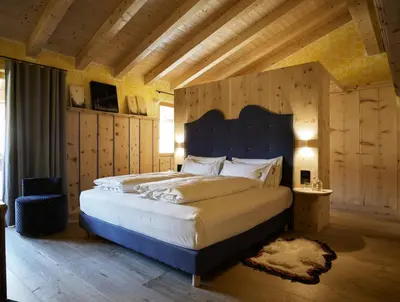 a bedroom with a large bed with a blue headboard at Dolomiti Lodge Alverà in Cortina dʼAmpezzo