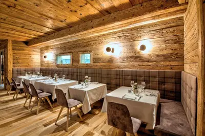 a dining room with tables and chairs and wooden walls at Dolomiti Lodge Alverà in Cortina dʼAmpezzo