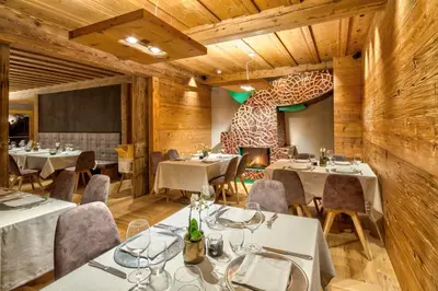 a restaurant with tables and chairs and a fireplace at Dolomiti Lodge Alverà in Cortina dʼAmpezzo