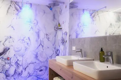 a bathroom with a sink and a white marble wall at Residence Rösch in Merano