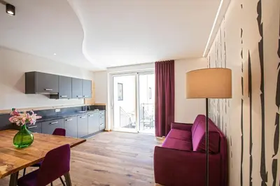 a living room with a table and a purple chair at Residence Rösch in Merano