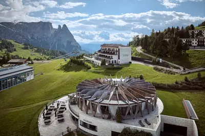 a building with a dome on top of a green field at COMO Alpina Dolomites in Alpe di Siusi