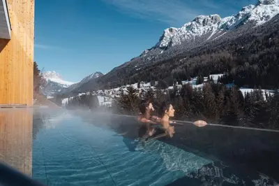 two people are sitting in a pool of water at Latemar - Hotel Suites Spa in Soraga