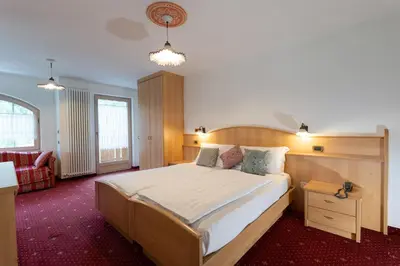 a bedroom with a large bed with a wooden headboard at Latemar - Hotel Suites Spa in Soraga