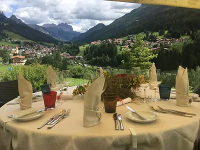 a table with a white table cloth with a view of mountains at Latemar - Hotel Suites Spa in Soraga
