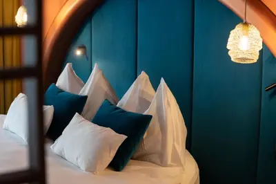 a bed with white pillows and a blue wall at Latemar - Hotel Suites Spa in Soraga