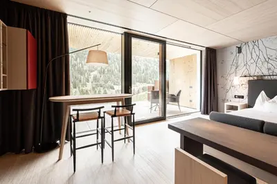 a hotel room with a bed and a table and chairs at Latemar - Hotel Suites Spa in Soraga