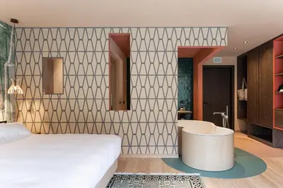 a bedroom with a bed and a tub and a bathroom at Latemar - Hotel Suites Spa in Soraga