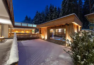 a house with a snow covered yard at night at Hotel Weiher Green Lake in Falzes