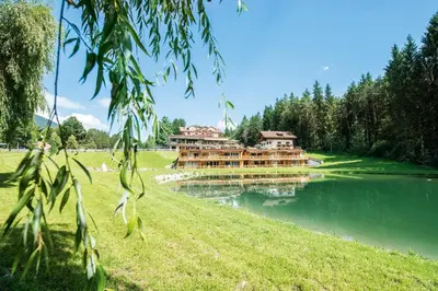 a building on the side of a lake at Hotel Weiher Green Lake in Falzes
