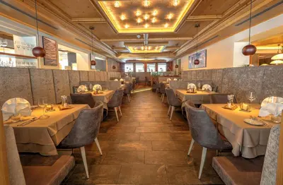 a restaurant with tables and chairs in a room at Hotel Weiher Green Lake in Falzes