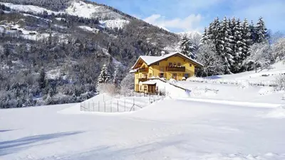 a house in the snow in front of a mountain at Eco-Baita Natura Spensierata in Canale San Bovo
