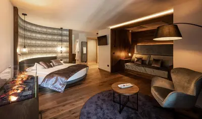 a hotel room with a bed and a couch at Ladinia Dolomites View - Adults Only in Pozza di Fassa