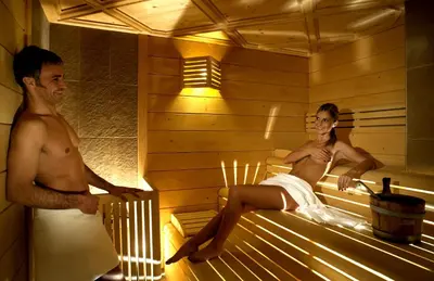 a man and a woman sitting in a sauna at Ladinia Dolomites View - Adults Only in Pozza di Fassa