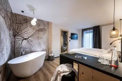 a bathroom with a large tub and a bed at Ladinia Dolomites View - Adults Only in Pozza di Fassa