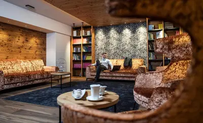 a man sitting on a couch in a library at Ladinia Dolomites View - Adults Only in Pozza di Fassa