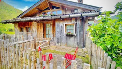 a wooden house with red chairs in front of it at Maso Franceschella in Carano