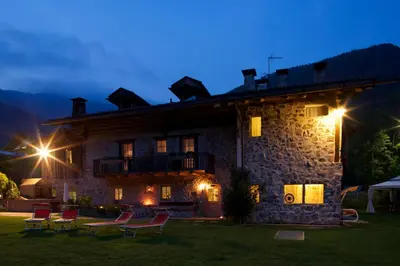 a building with chairs in front of it at night at Maso Franceschella in Carano