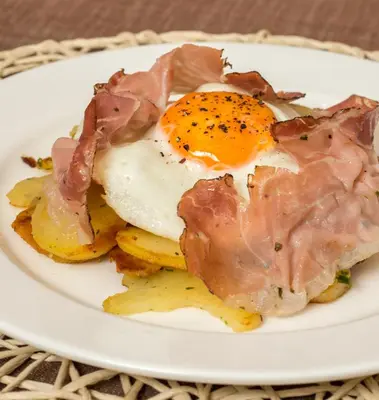an egg and bacon on a plate on a table at Maso Franceschella in Carano