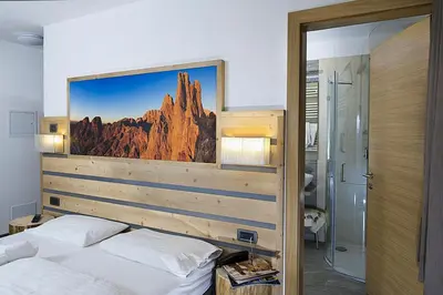a bedroom with a bed with a picture of a mountain at Hotel Aida in Pozza di Fassa