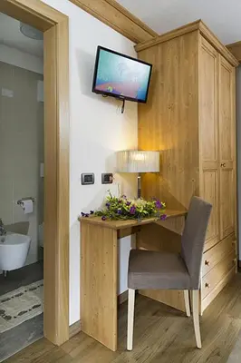 a bathroom with a desk with a television on a wall at Hotel Aida in Pozza di Fassa