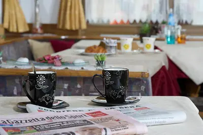 two black coffee cups sitting on top of a table at Hotel Aida in Pozza di Fassa