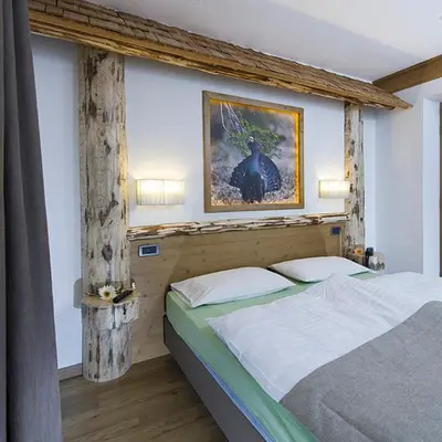 a bedroom with a bed with a picture on the wall at Hotel Aida in Pozza di Fassa