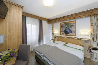 a bedroom with a bed with a picture on the wall at Hotel Aida in Pozza di Fassa