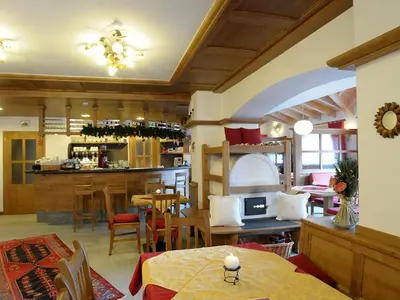 a restaurant with tables and chairs and a bar at Residence Panorama in Falcade