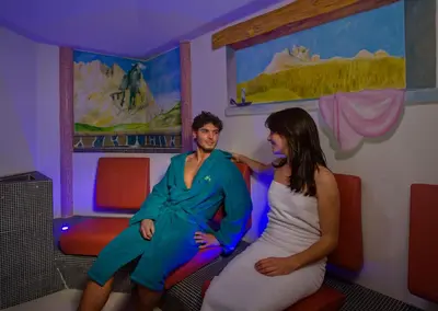 a man and a woman sitting on a couch in a room at Hotel Catinaccio Rosengarten in Moena