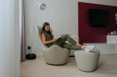 a woman sitting in a chair in a living room at Guesthouse Suiteseven in Merano