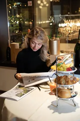 a woman sitting at a table reading a menu at Guesthouse Suiteseven in Merano
