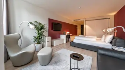 a hotel room with a bed and a chair at Guesthouse Suiteseven in Merano