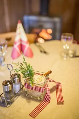a table with a glass container with flowers in it at Berggasthaus Agritur Moserhof in Braies
