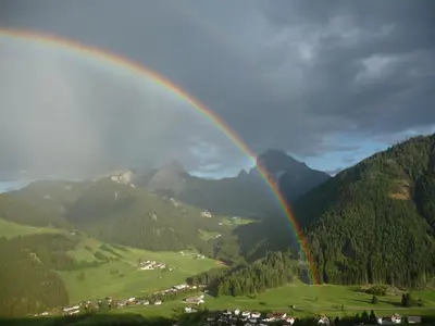 a rainbow over a valley with a town and mountains at Berggasthaus Agritur Moserhof in Braies