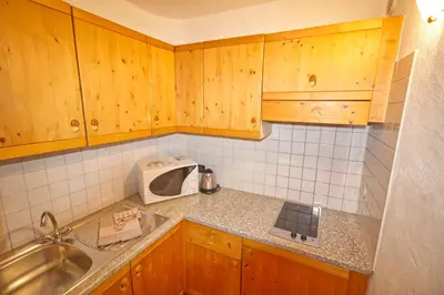 a kitchen with wooden cabinets and a sink and a microwave at Residence Miramonti in Daiano