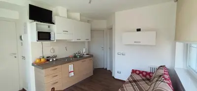 a small kitchen with white cabinets and a sink at Alla Fontana Termale in Carano