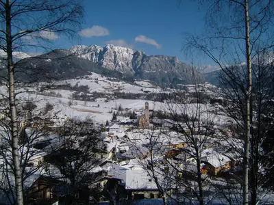 a town covered in snow with a mountain in the background at Alla Fontana Termale in Carano