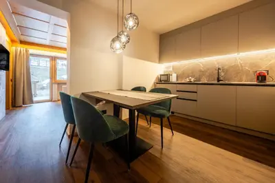 a kitchen with a wooden table and green chairs at Apartments Ursus in San Cassiano